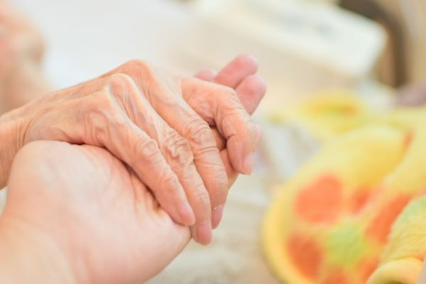 介護職員が高齢者の手を取る写真
