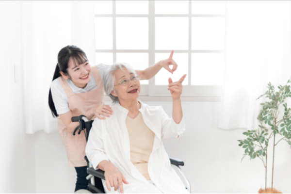 車椅子の高齢女性と介護ヘルパー女性の写真